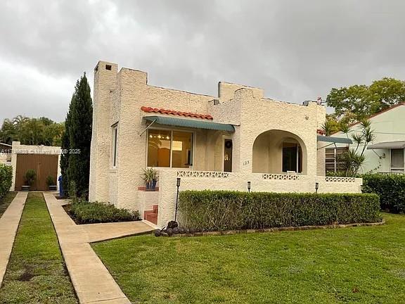 mediterranean / spanish home featuring a front yard, a tile roof, and stucco siding