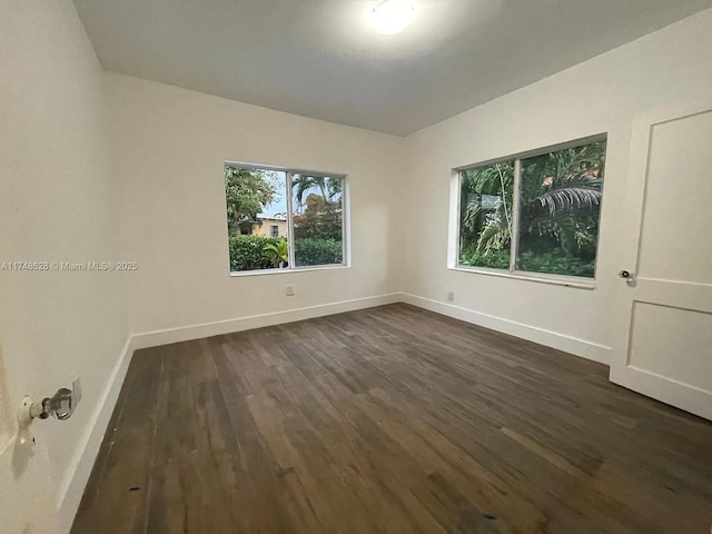 empty room featuring dark wood finished floors and baseboards