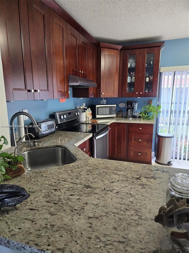 kitchen featuring appliances with stainless steel finishes, a sink, light stone counters, and under cabinet range hood