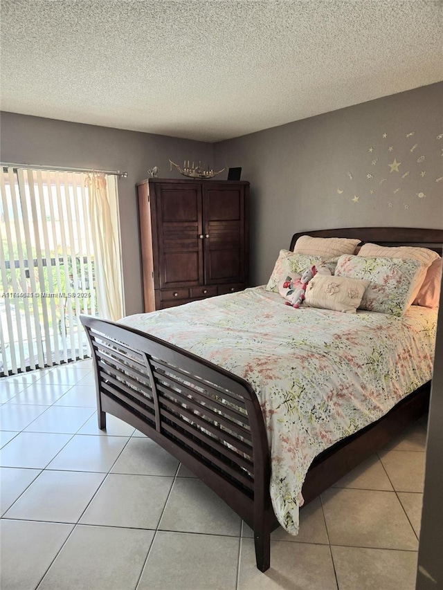 bedroom with a textured ceiling, light tile patterned flooring, and access to exterior