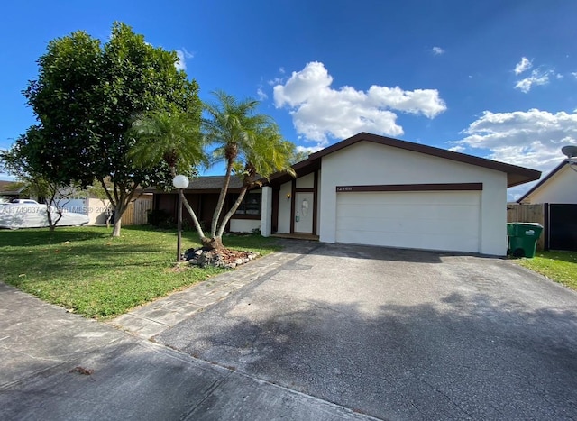 view of front facade with a garage, driveway, fence, a front lawn, and stucco siding