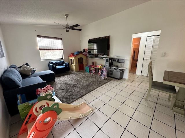 living room featuring light tile patterned floors, ceiling fan, and a textured ceiling