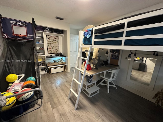 bedroom with visible vents and wood finished floors