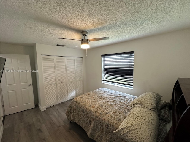 bedroom with a textured ceiling, visible vents, a ceiling fan, a closet, and dark wood-style floors