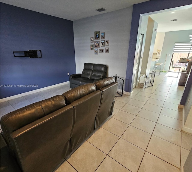 living area featuring light tile patterned flooring, visible vents, and baseboards