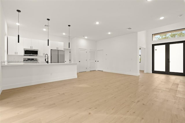 unfurnished living room featuring french doors, light wood finished floors, recessed lighting, visible vents, and baseboards