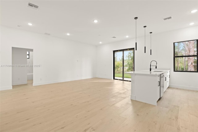 kitchen with visible vents, open floor plan, light countertops, hanging light fixtures, and light wood finished floors