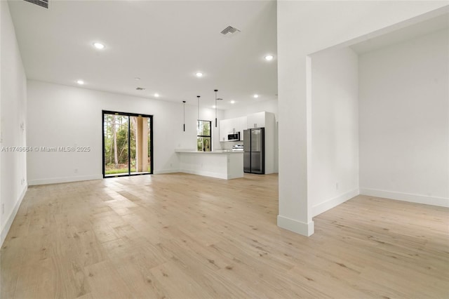 unfurnished living room with light wood-type flooring, visible vents, baseboards, and recessed lighting