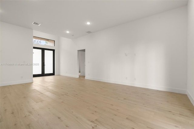 spare room featuring light wood-style floors, french doors, visible vents, and baseboards