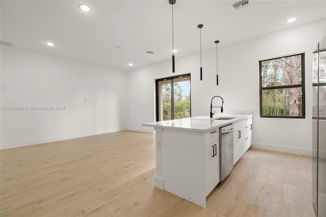 kitchen with pendant lighting, light countertops, stainless steel dishwasher, white cabinetry, and a sink