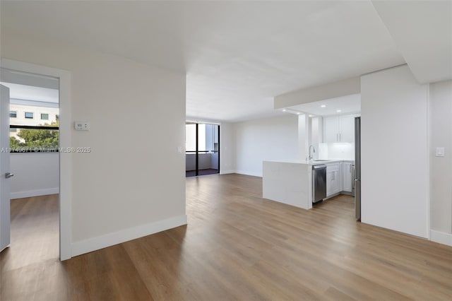 interior space with a sink, light wood-style flooring, and baseboards