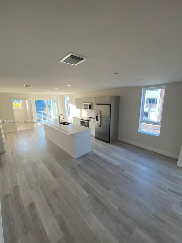 2561 NE 193rd St Unit 1202, Miami, FL 33180 - kitchen with stainless steel appliances, a sink, white cabinets, open floor plan, and an island with sink