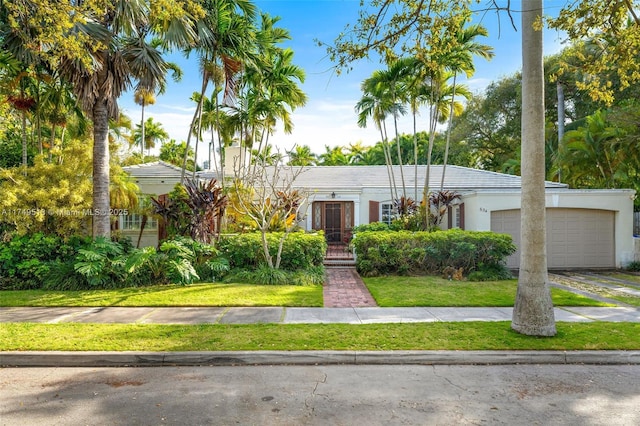 view of front of house with driveway, a front lawn, an attached garage, and stucco siding