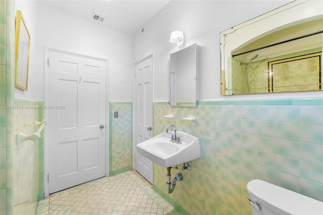 bathroom with visible vents, wainscoting, toilet, tile patterned flooring, and tile walls