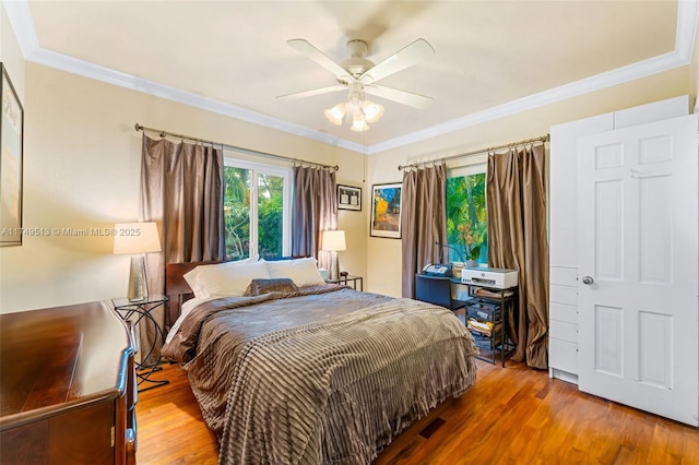 bedroom featuring wood finished floors, a ceiling fan, and crown molding