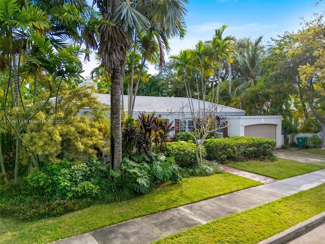 view of front of property with an attached garage, a front lawn, and stucco siding