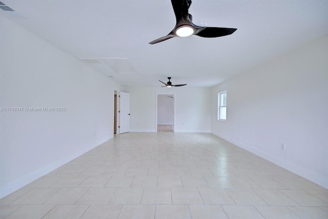 unfurnished room featuring visible vents, a ceiling fan, attic access, a textured ceiling, and baseboards