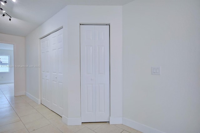 interior space featuring light tile patterned floors, baseboards, and rail lighting