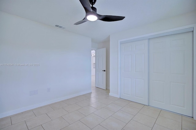 unfurnished bedroom with light tile patterned floors, a closet, visible vents, a ceiling fan, and baseboards