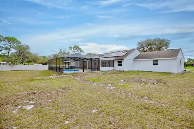 rear view of property featuring a lanai, fence, a yard, a fenced in pool, and stucco siding