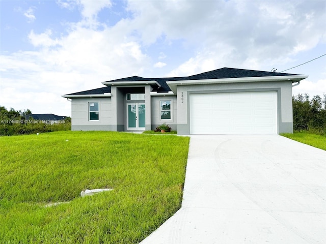 prairie-style house with a garage, concrete driveway, a front lawn, and stucco siding