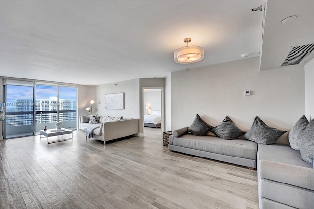 living area with a view of city, expansive windows, light wood-type flooring, and visible vents