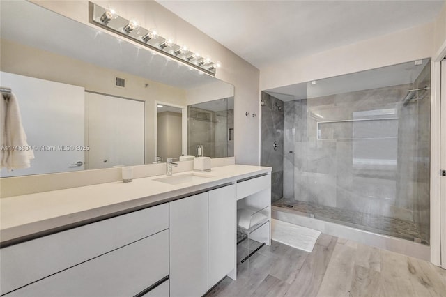 full bathroom featuring visible vents, walk in shower, vanity, and wood finished floors