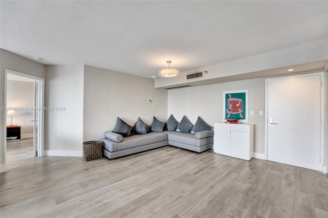 living room with light wood-style floors, visible vents, and baseboards