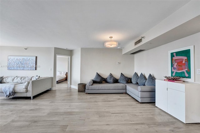 living room with light wood-type flooring, baseboards, and visible vents