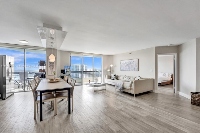 living area with a view of city, baseboards, wood finished floors, and floor to ceiling windows