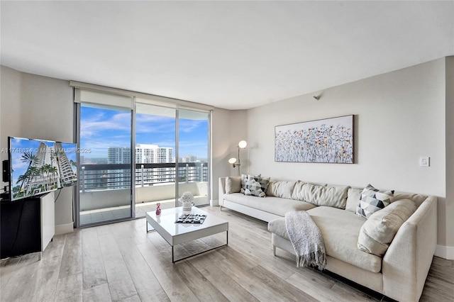 living area featuring baseboards, a wall of windows, and light wood-style floors