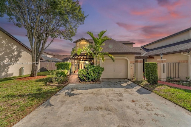 view of front of house with concrete driveway, an attached garage, fence, a yard, and stucco siding