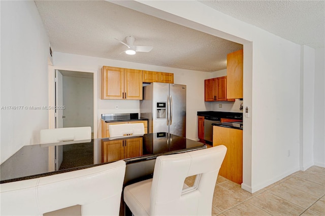 kitchen featuring dark countertops, appliances with stainless steel finishes, a textured ceiling, and light tile patterned flooring