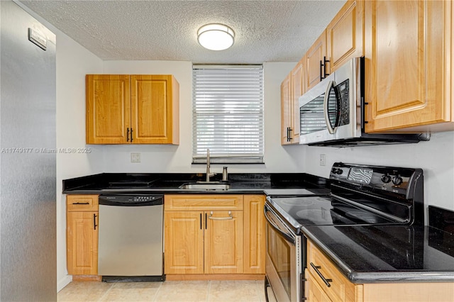 kitchen featuring a textured ceiling, stainless steel appliances, light tile patterned floors, and a sink