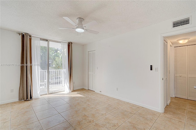 unfurnished room featuring visible vents, ceiling fan, a textured ceiling, and light tile patterned flooring