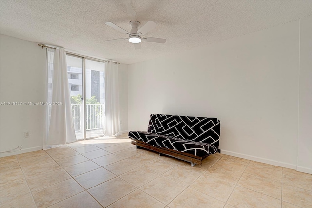 living area with a ceiling fan, baseboards, a textured ceiling, and light tile patterned flooring