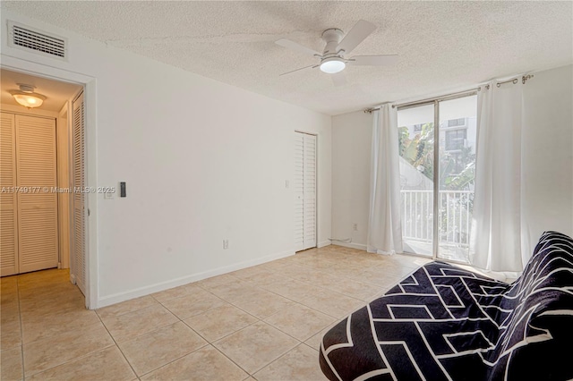 living area with visible vents, a textured ceiling, and light tile patterned floors