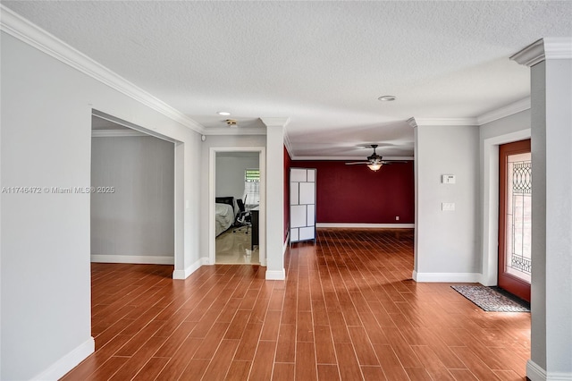 spare room with a textured ceiling, wood finished floors, baseboards, and ornamental molding