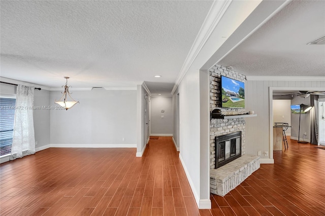 unfurnished living room featuring a textured ceiling, wood finished floors, a fireplace, and ornamental molding