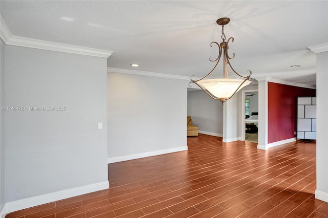 spare room with a textured ceiling, dark wood-type flooring, baseboards, and ornamental molding