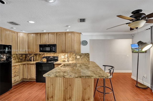 kitchen featuring a sink, visible vents, black appliances, and a peninsula