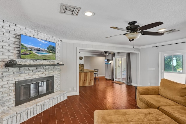 unfurnished living room with dark wood-type flooring, a fireplace, visible vents, and ornamental molding