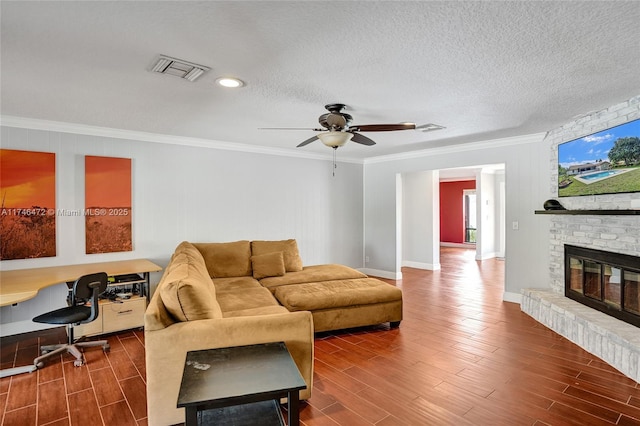 living area with crown molding, a brick fireplace, visible vents, and wood tiled floor