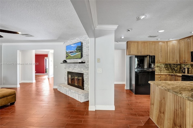 kitchen featuring a brick fireplace, visible vents, open floor plan, and freestanding refrigerator