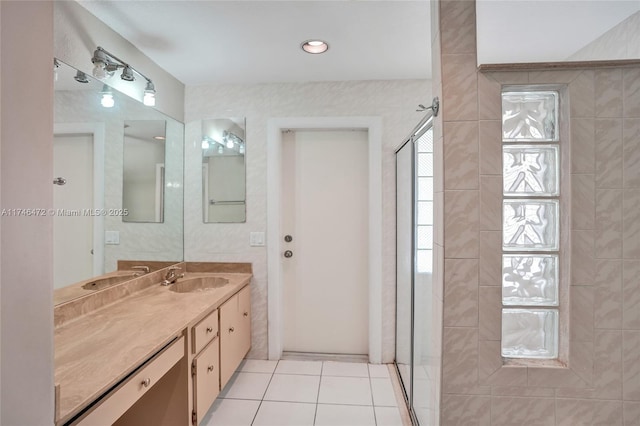 bathroom with tile patterned floors, tile walls, vanity, and a tile shower