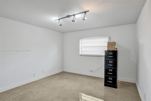 unfurnished room with baseboards, a textured ceiling, and track lighting