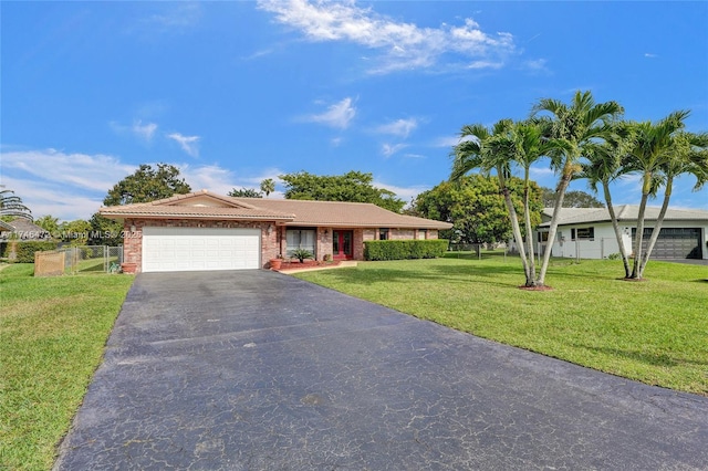 single story home with brick siding, a front lawn, fence, a garage, and driveway