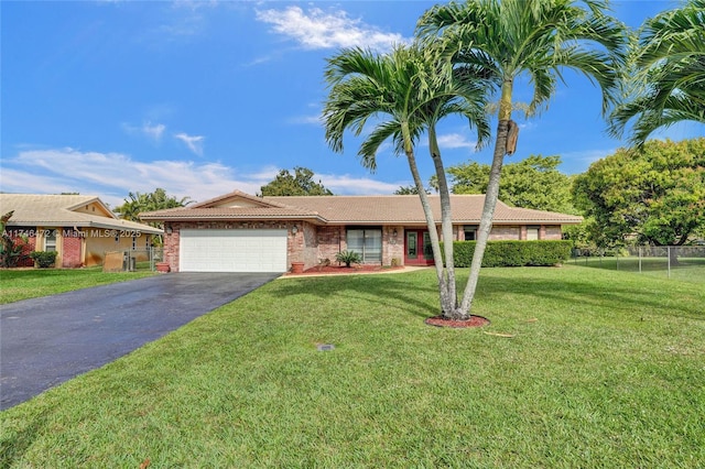 ranch-style house with an attached garage, fence, a tiled roof, a front yard, and driveway