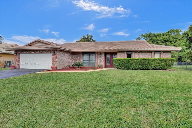 ranch-style house with a front yard, driveway, an attached garage, a tile roof, and brick siding