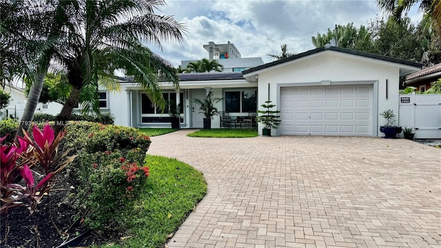 single story home featuring a garage, decorative driveway, and stucco siding